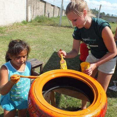 A Projects Abroad volunteer paints with children in Argentina on our project for teenagers A volunteer painting tyres with children in Argentina on our project for high school students